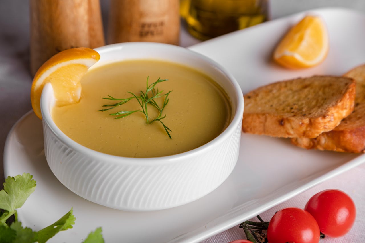 A delicious bowl of creamy soup garnished with dill and served with toasted bread and lemon.